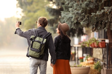 Photo of Couple of travelers with camera on city street, back view