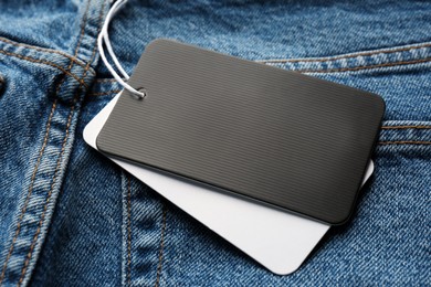 Photo of Cardboard tags with space for text on blue jeans, closeup