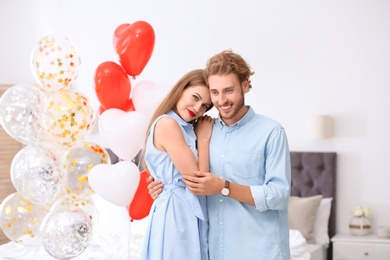 Young couple with air balloons in bedroom. Celebration of Saint Valentine's Day