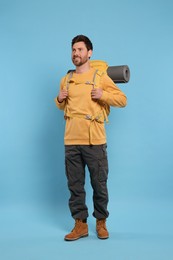 Photo of Happy man with backpack on light blue background. Active tourism