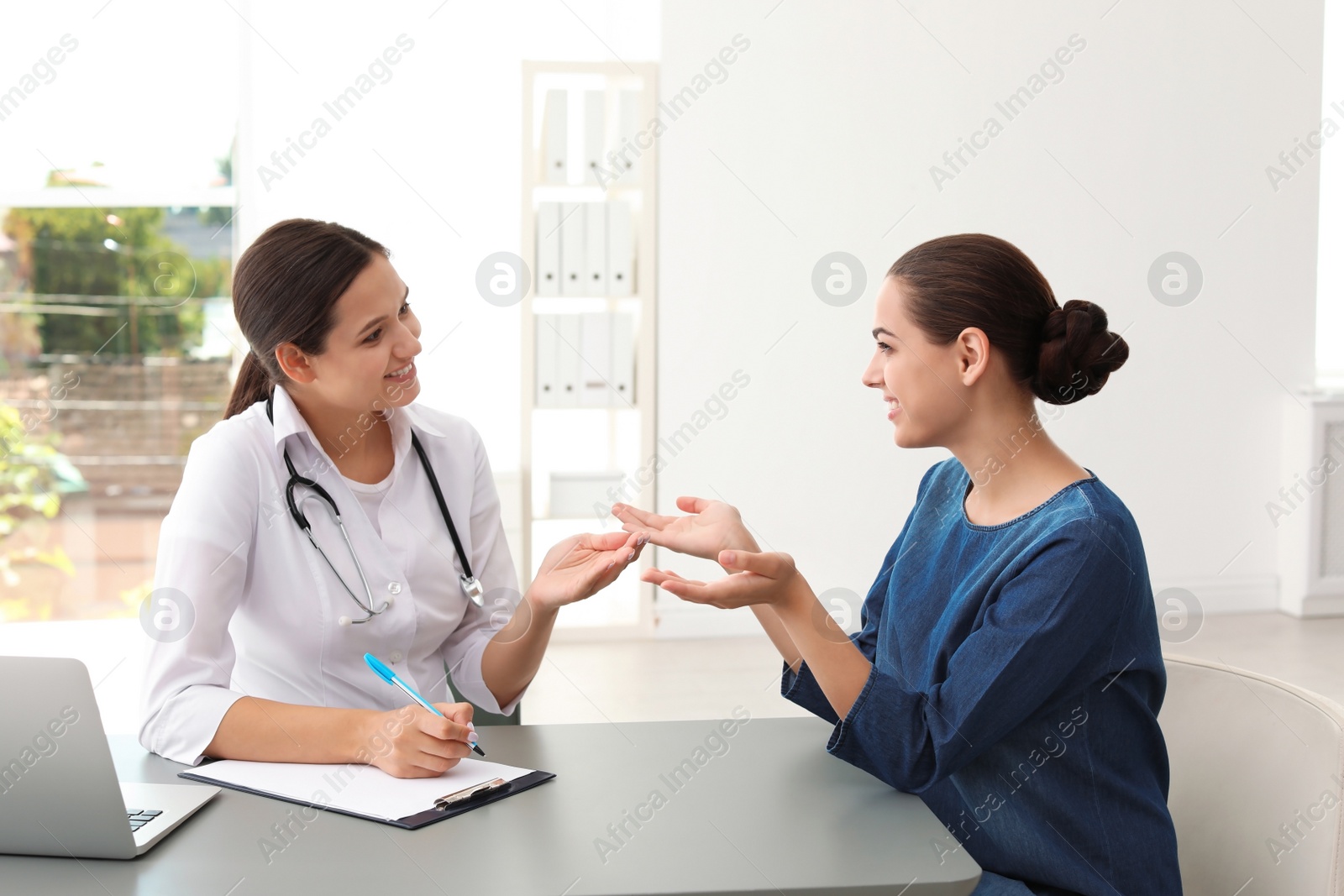 Photo of Young doctor listening to patient's complaints in hospital