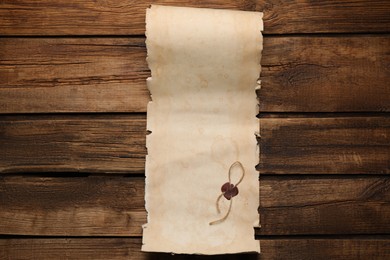 Photo of Sheet of old parchment paper with wax stamp on wooden table, top view. Space for design