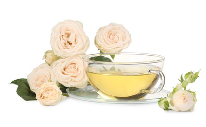 Aromatic herbal tea in glass cup and roses isolated on white