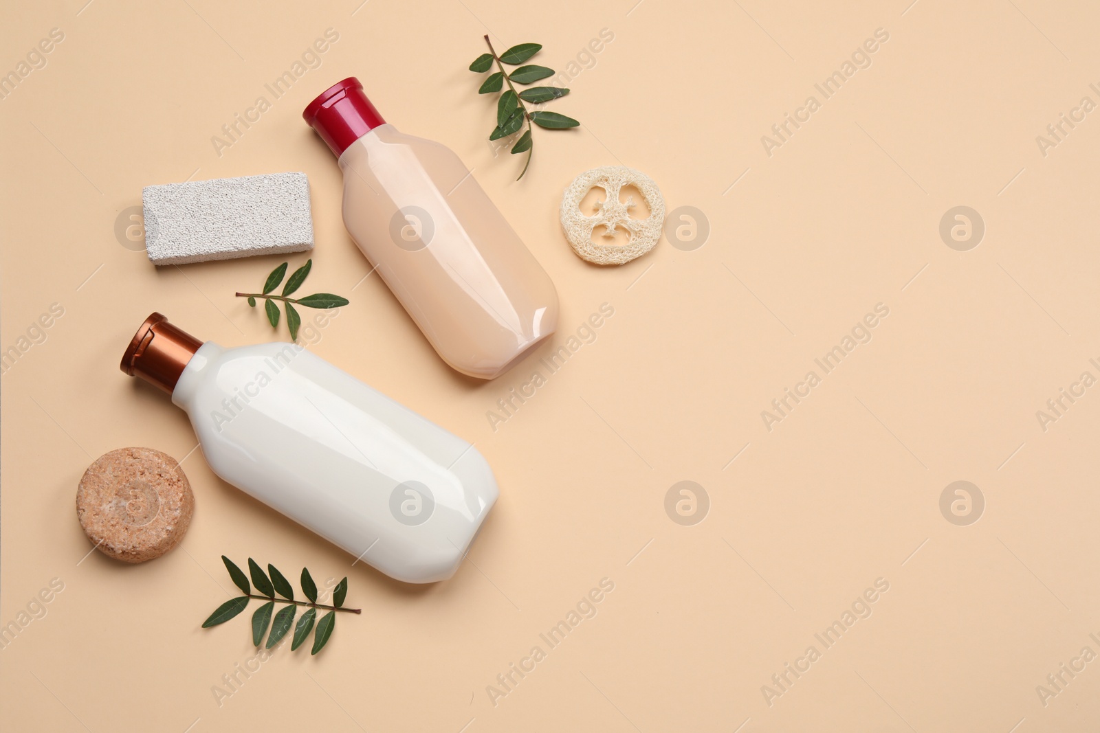 Photo of Flat lay composition with solid shampoo bar and bottles of cosmetic product on beige background, space for text