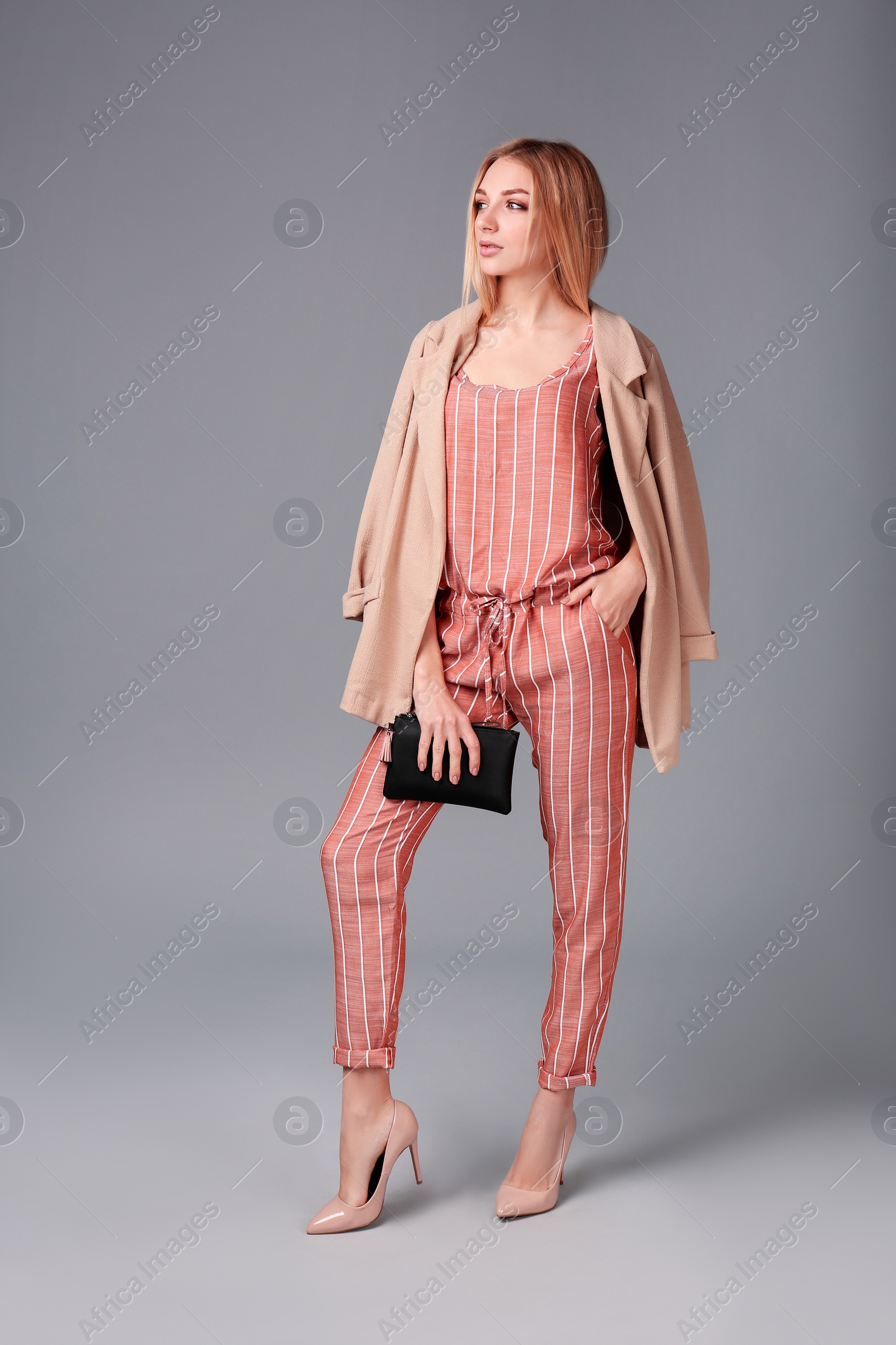 Photo of Young stylish woman in trendy shoes with bag on grey background