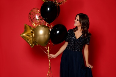 Photo of Happy woman with air balloons on red background. Christmas party