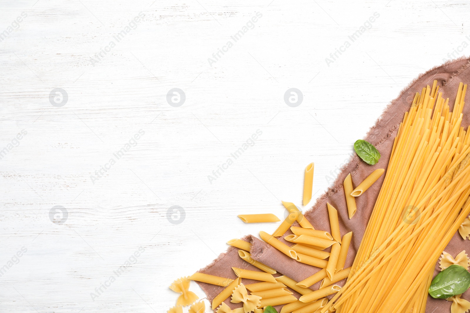 Photo of Beautiful composition with different raw pasta on wooden background, top view