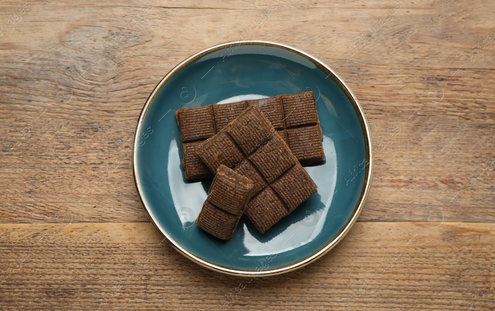 Photo of Blue plate with delicious and healthy hematogen on wooden table, top view