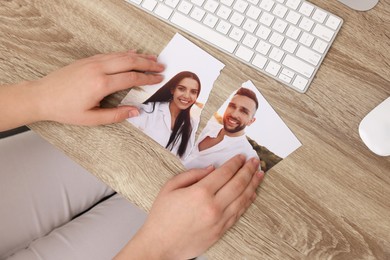 Woman holding torn photo at wooden table indoors, top view. Divorce concept