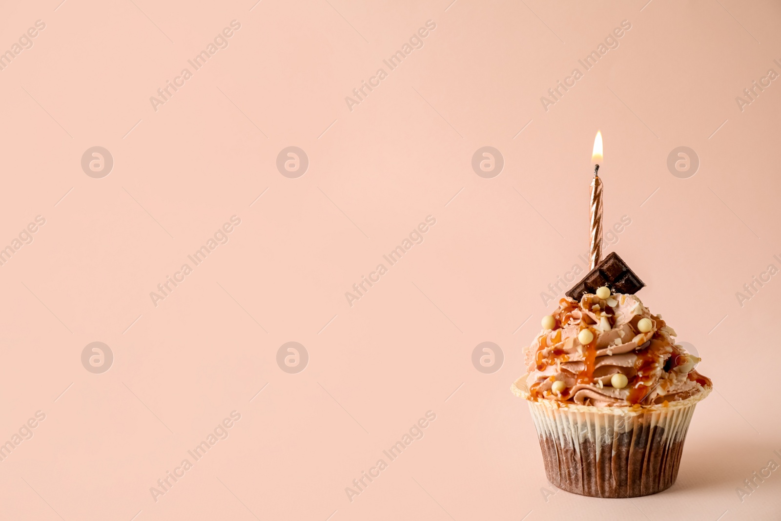 Photo of Delicious birthday cupcake with burning candle on pink background, space for text