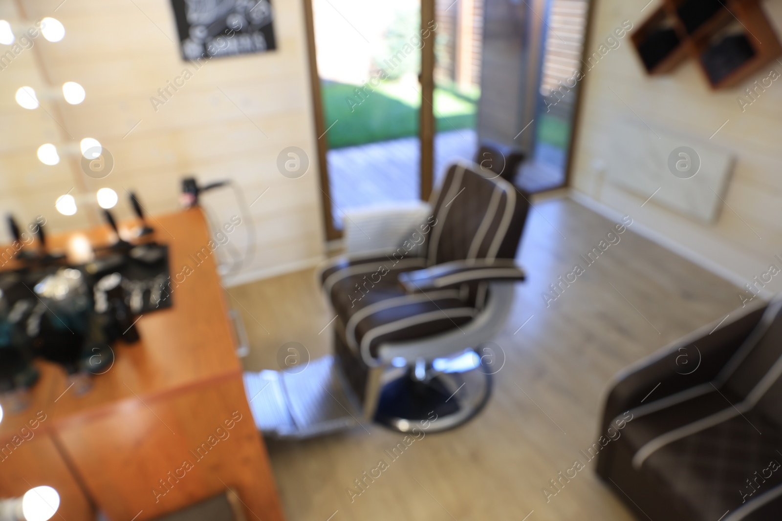 Photo of Blurred view of stylish hairdresser's workplace with professional armchair in barbershop