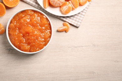 Photo of Flat lay composition with delicious tangerine jam on wooden table. Space for text