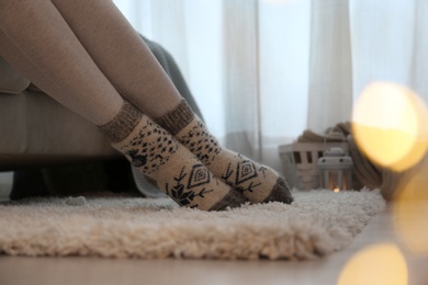 Photo of Woman wearing knitted socks at home, closeup. Warm clothes