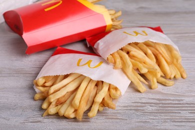 MYKOLAIV, UKRAINE - AUGUST 12, 2021: Small and big portions of McDonald's French fries on white wooden table, closeup
