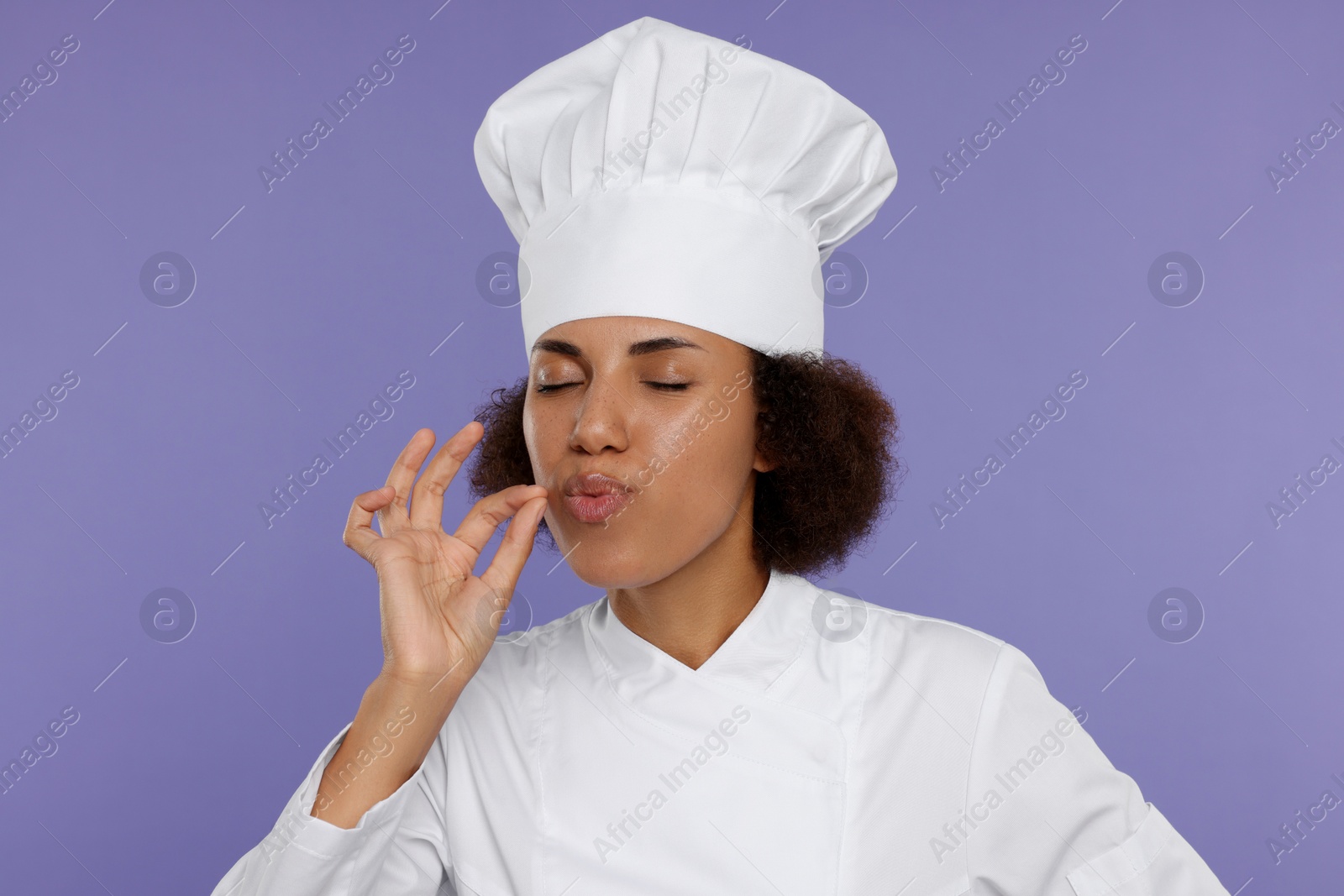 Photo of Happy female chef in uniform showing perfect sign on purple background