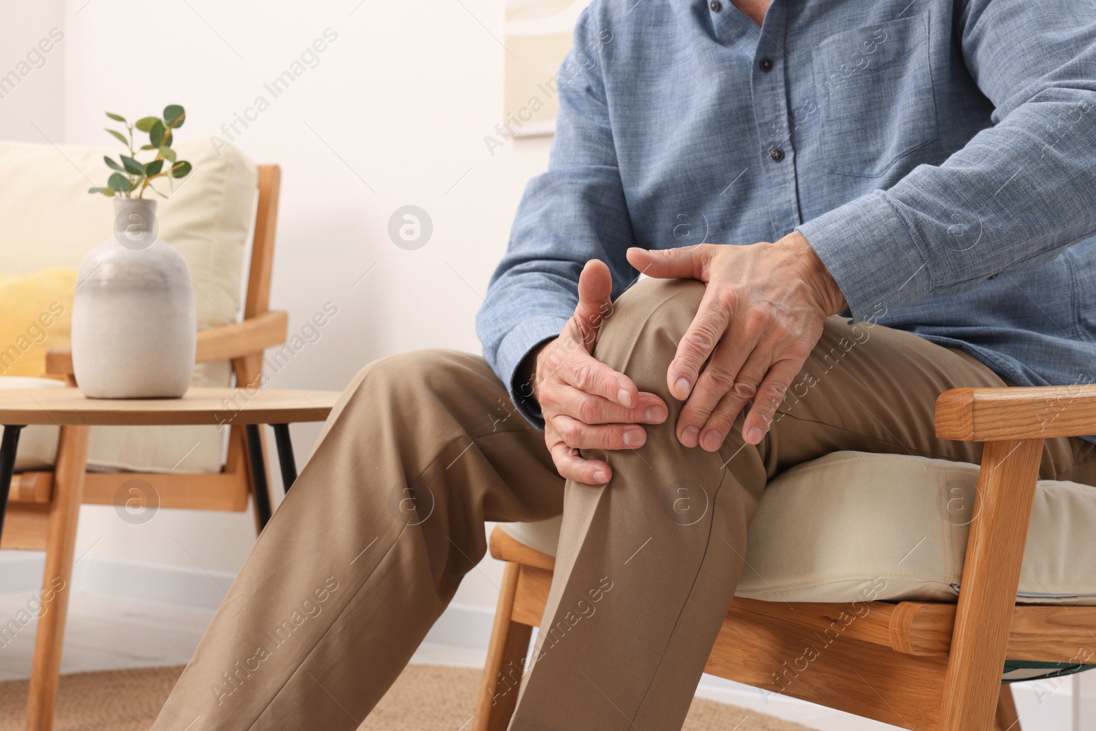 Photo of Senior man suffering from pain in his knee at home, closeup. Arthritis symptoms