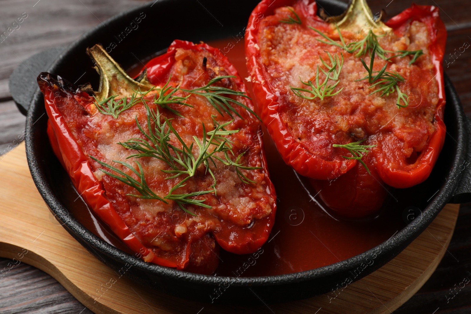 Photo of Tasty stuffed peppers in dish on wooden table, closeup