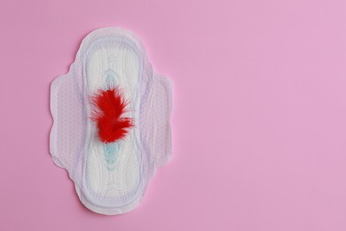 Menstrual pad and feather on pink background, top view. Space for text