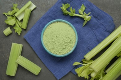 Natural celery powder in bowl and fresh stalks on grey table, flat lay