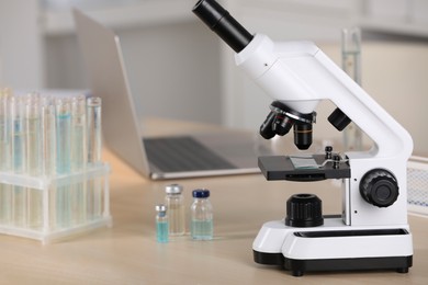Photo of Modern medical microscope on wooden table in laboratory, space for text