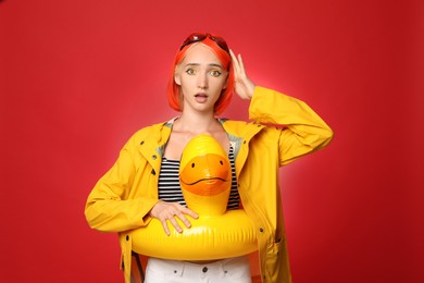 Photo of Emotional young woman with bright dyed hair and inflatable ring on color background