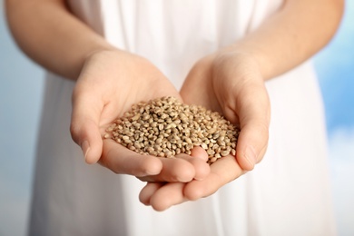 Photo of Woman holding heap of hemp seeds, closeup