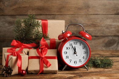 Christmas gifts, fir branches and alarm clock on wooden table. Boxing day