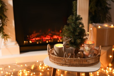 Photo of Composition with decorative reindeer and Christmas tree near fireplace in room, space for text
