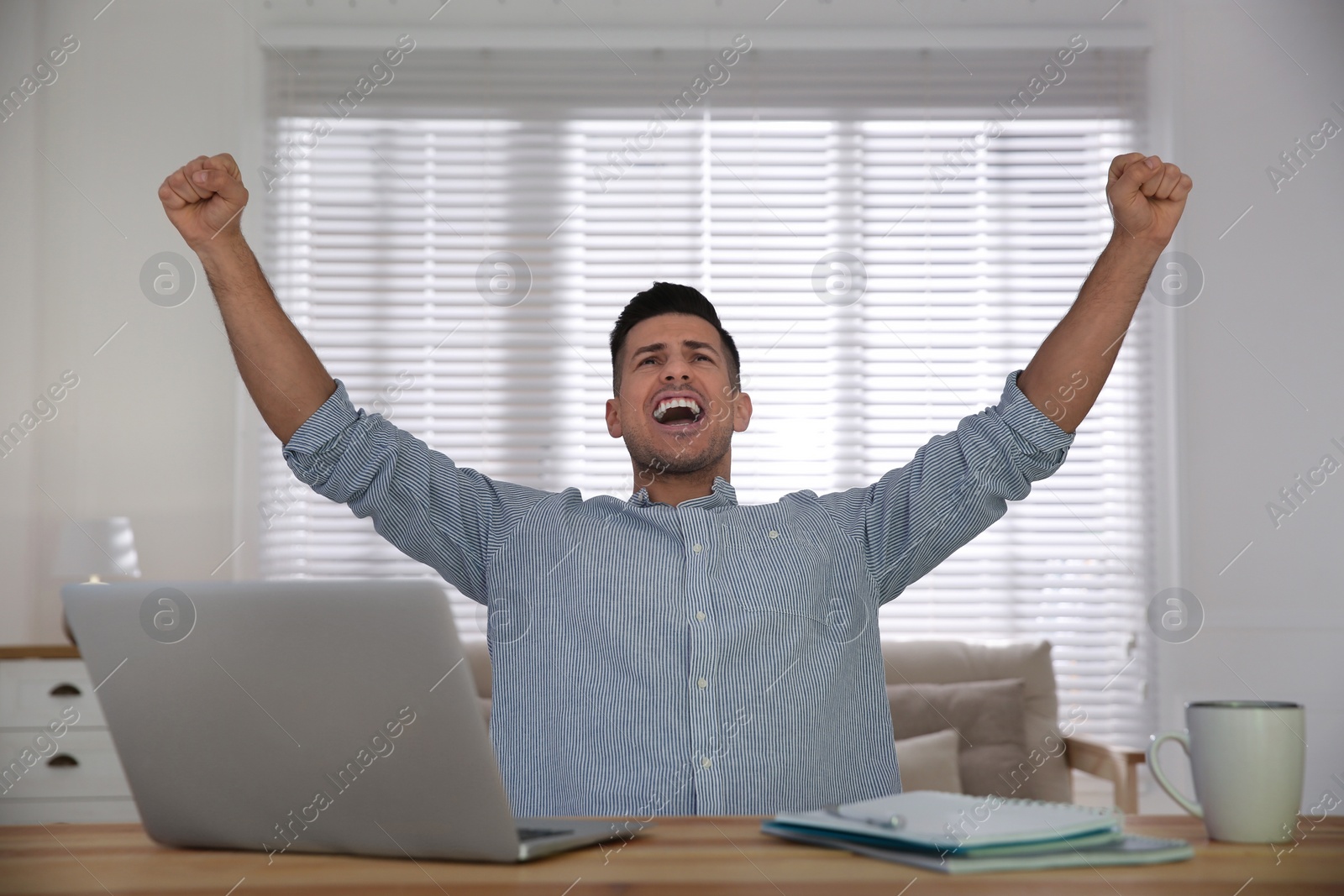 Photo of Emotional man participating in online auction using laptop at home