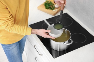 Man pouring delicious soup into bowl in kitchen, closeup