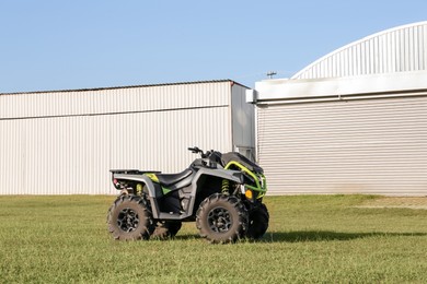 Photo of Modern quad bike in field near hangars on sunny day