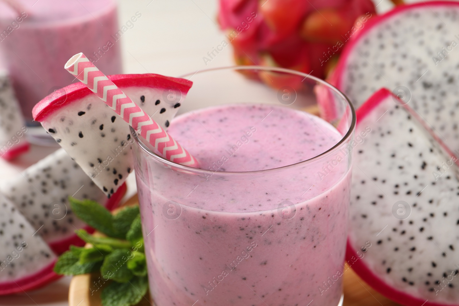 Photo of Delicious pitahaya smoothie and fresh fruits on table, closeup