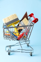 Different construction tools in shopping cart on light blue background