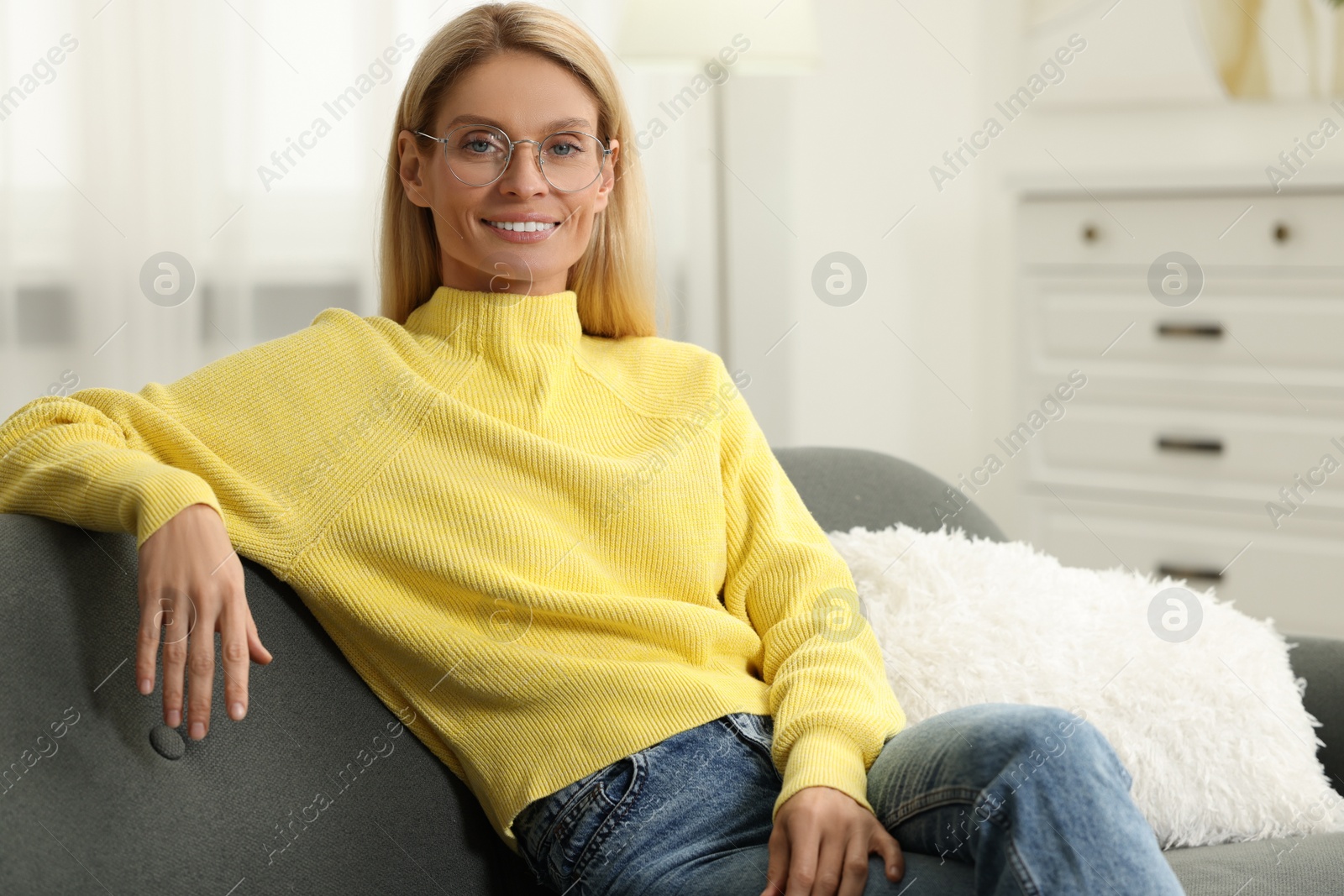 Photo of Happy woman in stylish glasses on sofa indoors