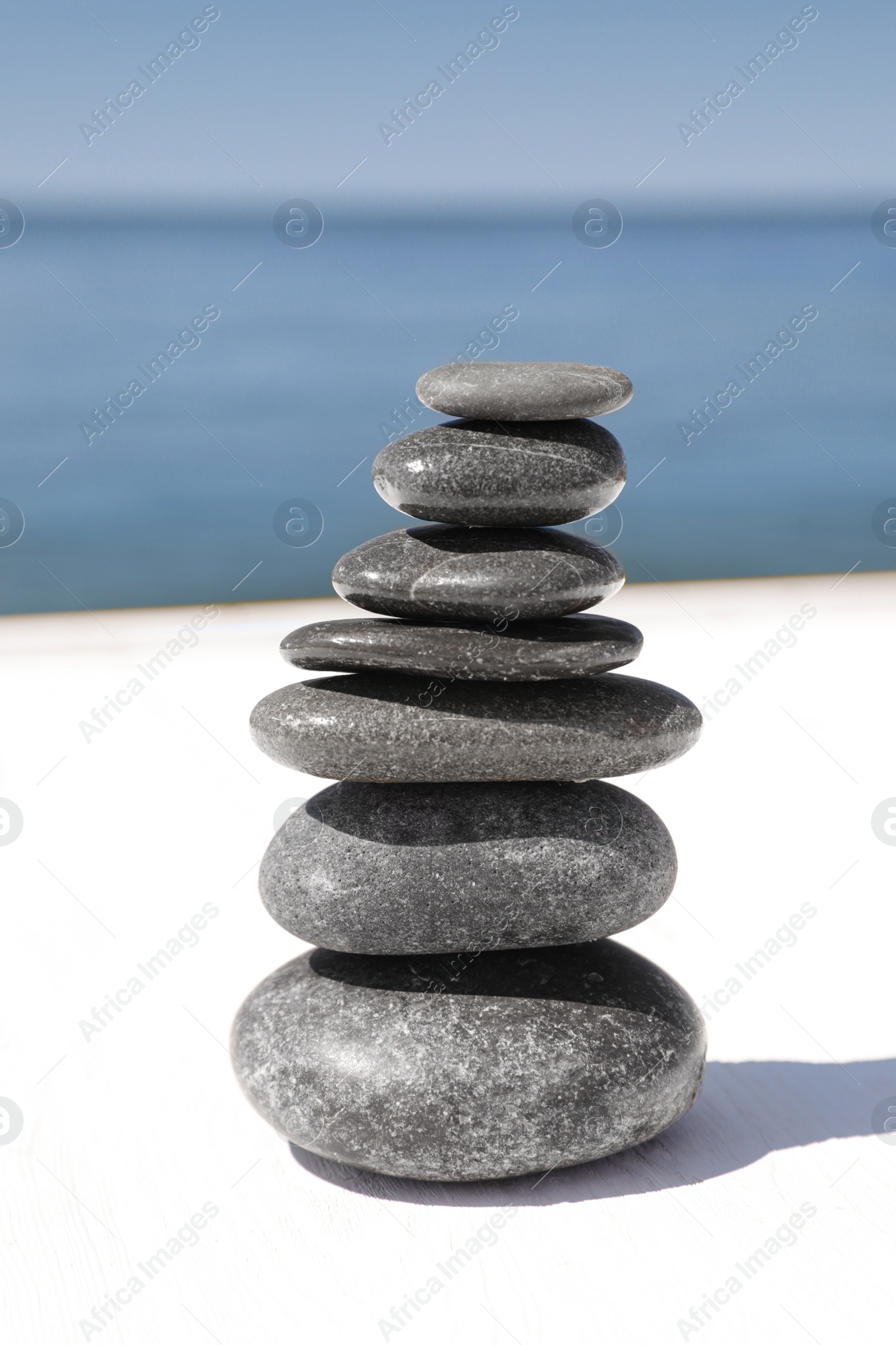 Photo of Stack of stones on wooden pier near sea. Zen concept