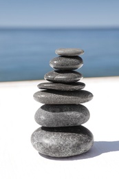 Photo of Stack of stones on wooden pier near sea. Zen concept