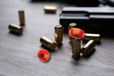 Image of Beautiful poppy flowers, bullets and handgun on wooden table, closeup. Peace instead of war