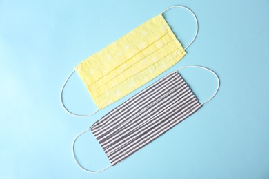 Homemade protective face masks on light blue background, flat lay