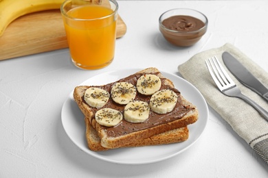 Photo of Slice of bread with chocolate paste and banana on white table