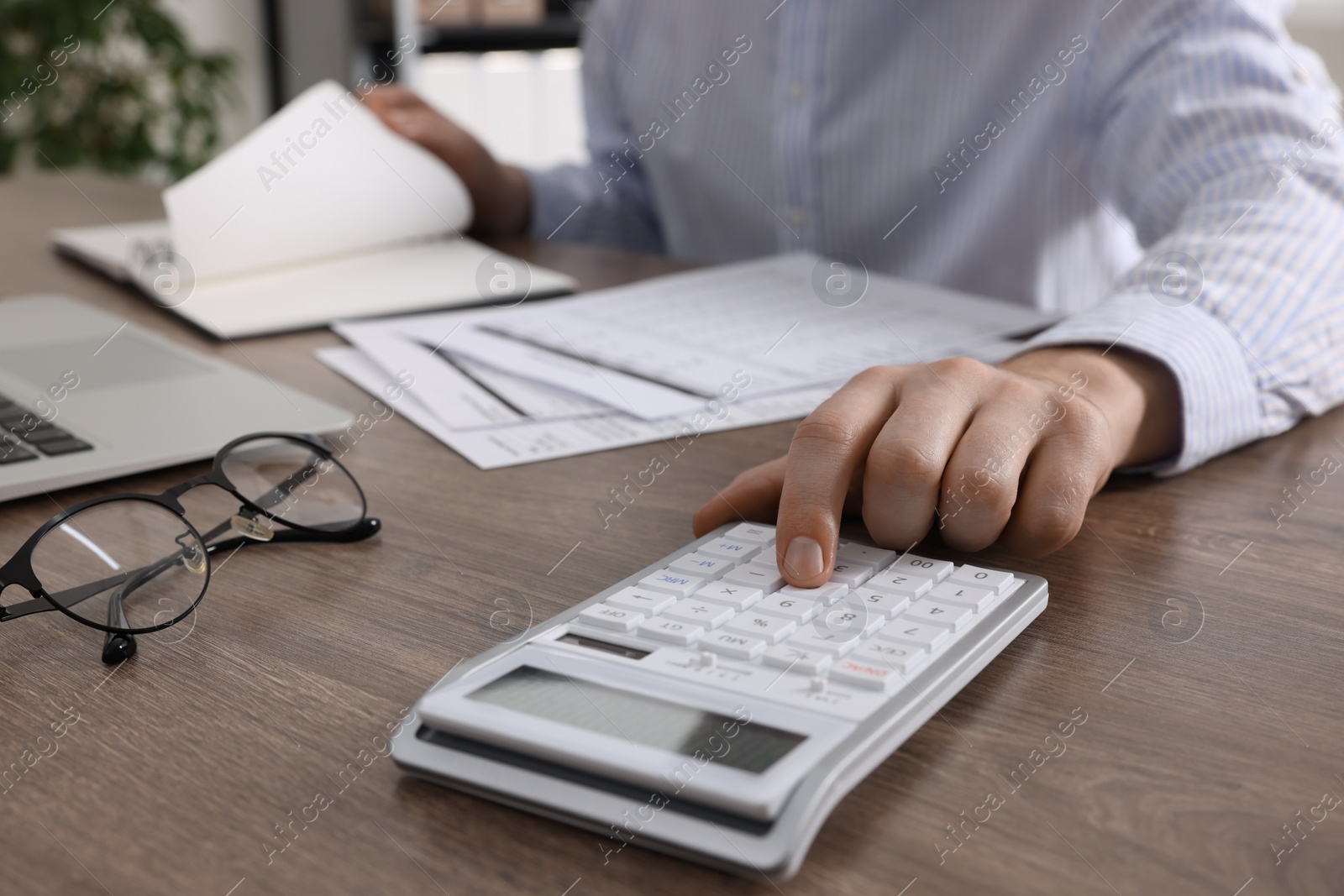 Photo of Man using calculator at wooden table indoors, closeup