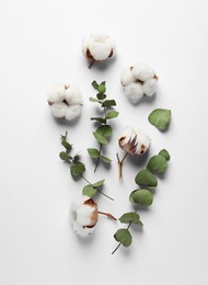 Photo of Fluffy cotton flowers and leaves on white background, flat lay