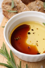 Photo of Bowl of organic balsamic vinegar with oil, bread slices and spices on wooden board, closeup