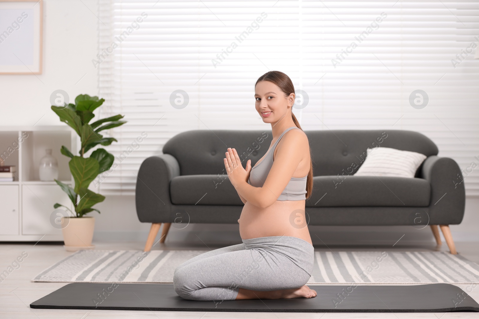 Photo of Pregnant woman meditating on yoga mat at home