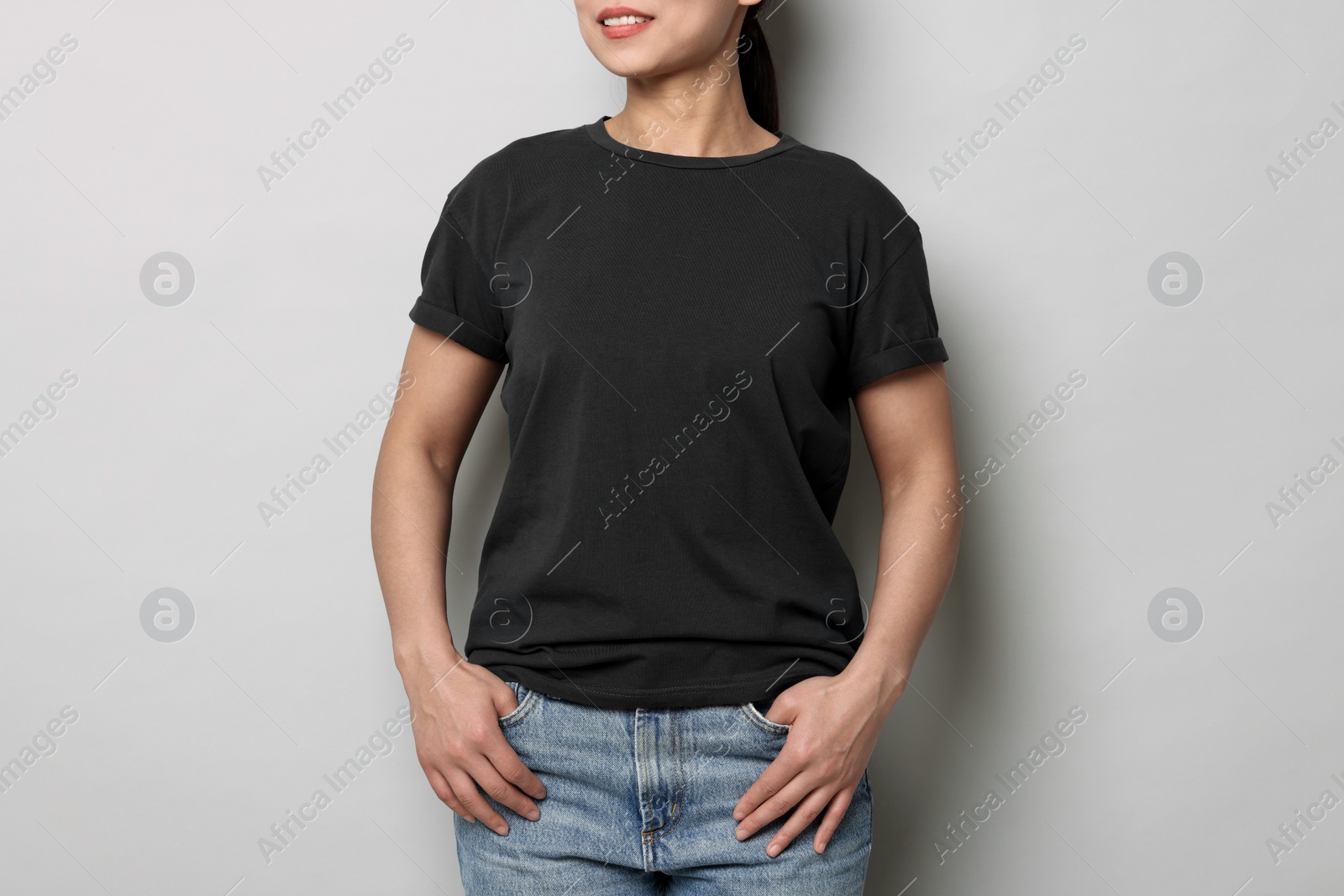 Photo of Woman wearing black t-shirt on light grey background, closeup