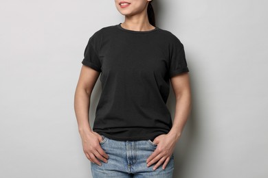 Photo of Woman wearing black t-shirt on light grey background, closeup