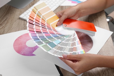 Photo of Woman with color palette samples at table, closeup