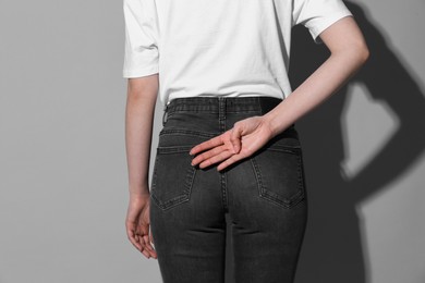 Photo of Woman showing open palm behind her back on grey background, back view