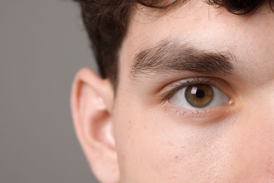 Man with beautiful eyes on grey background, closeup