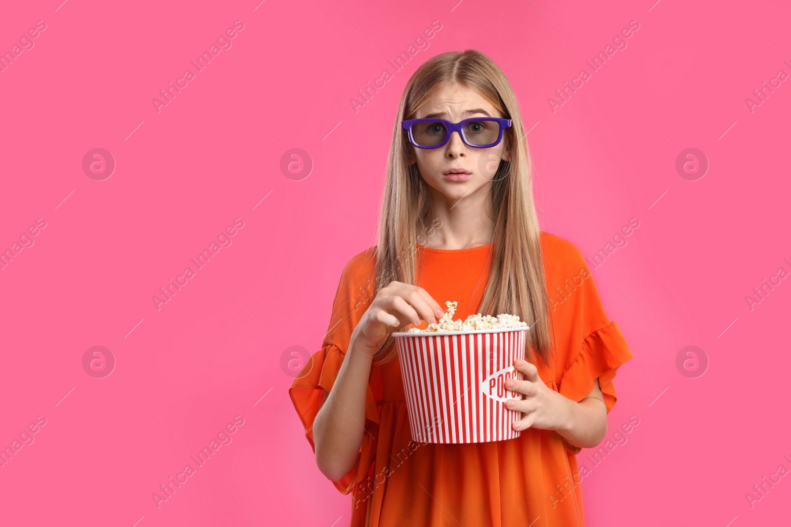 Photo of Emotional teenage girl with 3D glasses and popcorn during cinema show on color background