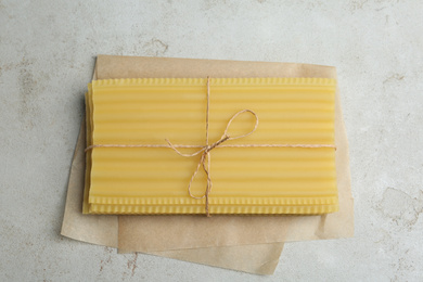 Uncooked lasagna sheets tied with rope on light grey table, top view